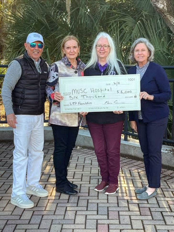 Four adults stand outdoors, smiling and holding a large check for $6,000 made out to MUSC Hospital from the LTP Foundation. Palm trees and a brick walkway are visible in the background.