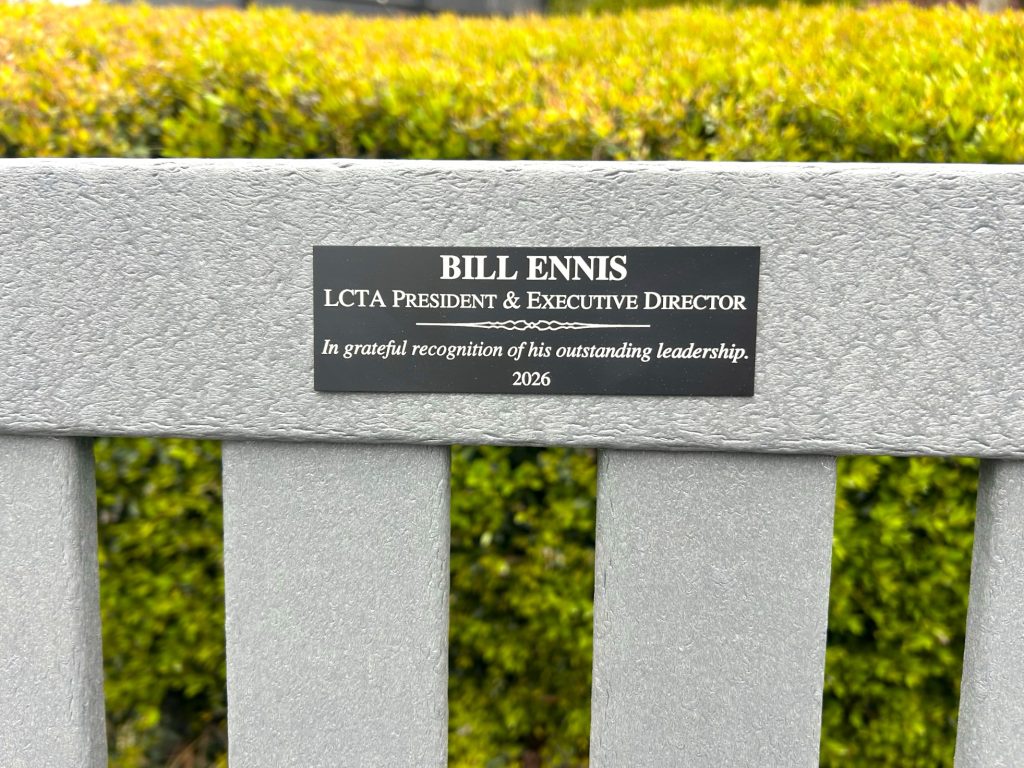 A plaque on a gray bench reads: