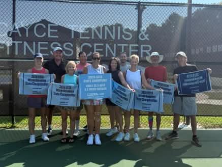 A group of 11 people pose on a tennis court, smiling and holding banners celebrating their 2023 USTA Mixed Doubles State Championships at the Jayce Tennis & Fitness Center.